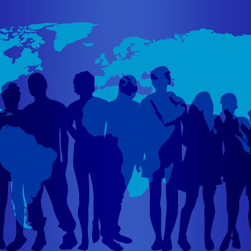 A group of people silhouetted against a map of the world.